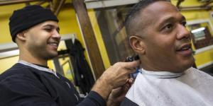 A man gets his hair cut at a barber shop.